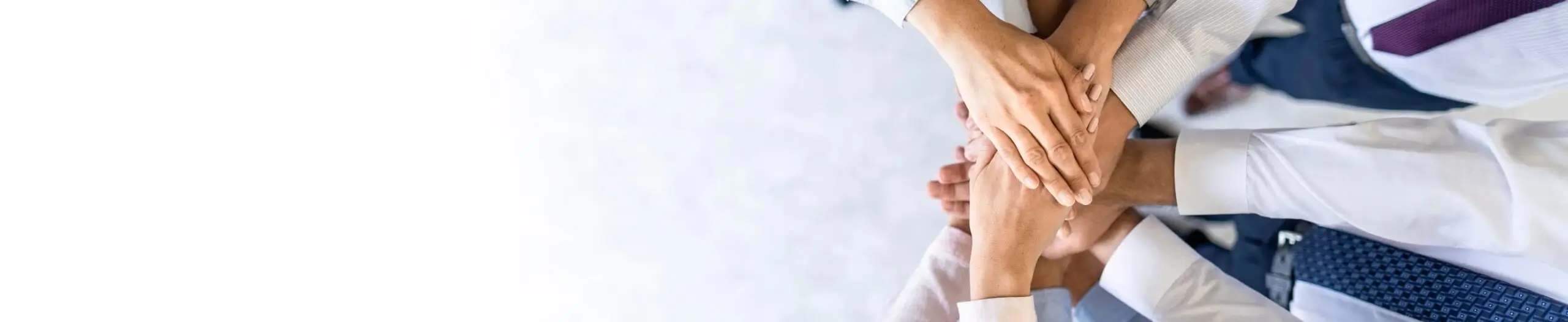 A diverse team stacks their hands together in a show of collaboration, trust, and unity, representing teamwork, partnership, and shared business success.