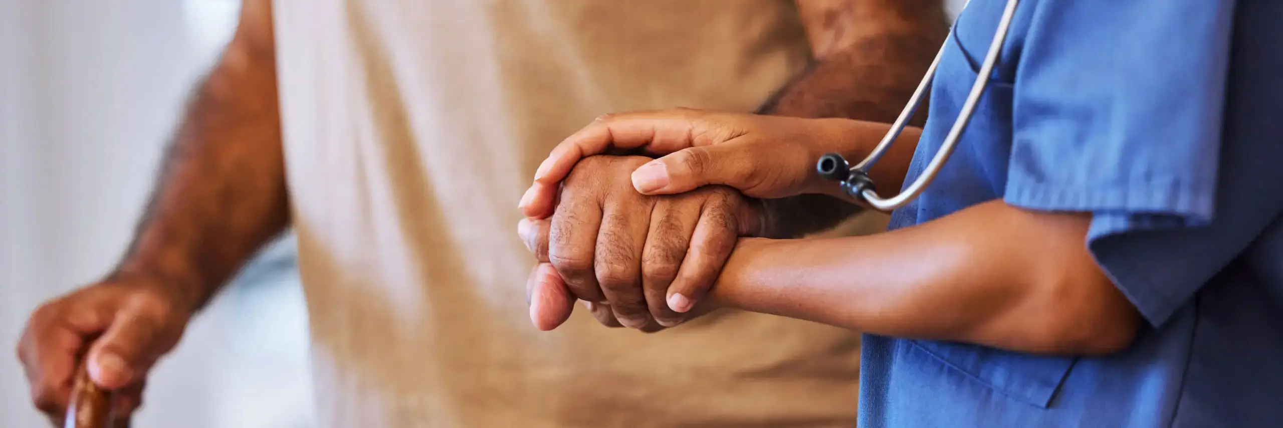 Compassionate healthcare professional in scrubs holding a patient's hand, representing quality care, support, and patient-centered healthcare.