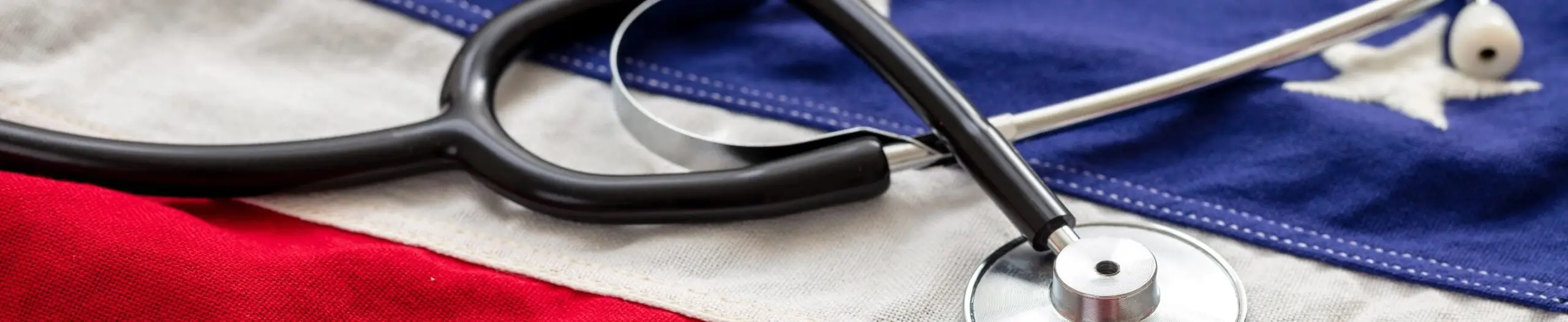 Close-up image of a black stethoscope resting on a United States flag, symbolizing healthcare services, medical care, veteran support, and commitment to serving communities across America.